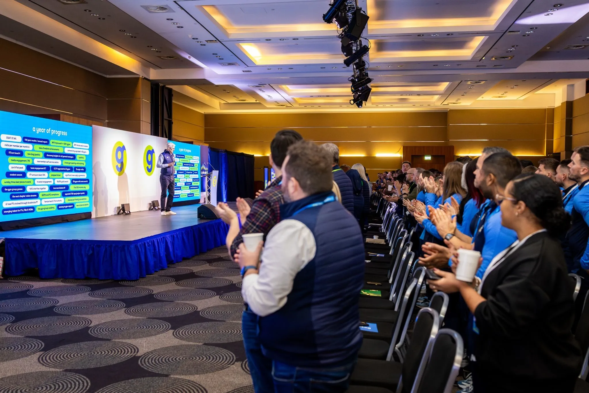 A photo of conference stage with presentation slides created by Nadia Vizg at The Gym Group conference.